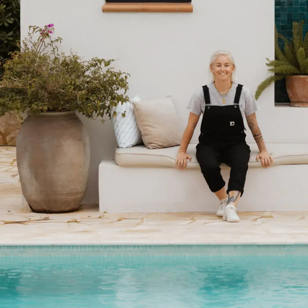 Buchhaltungs-Mentorin Melanie Göggel sitzt auf einem cremefarbenen Sofa an einem Swimmingpool.